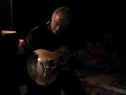 Man in a dark room playing an electric guitar